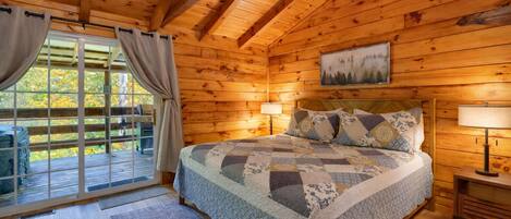Un dormitorio de cabaña de madera con una cama grande, dos lámparas de noche y una ventana con cortinas.