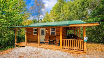 Ein rustikales Blockhaus mit Veranda, zwei Stühlen und einem kleinen Tisch.