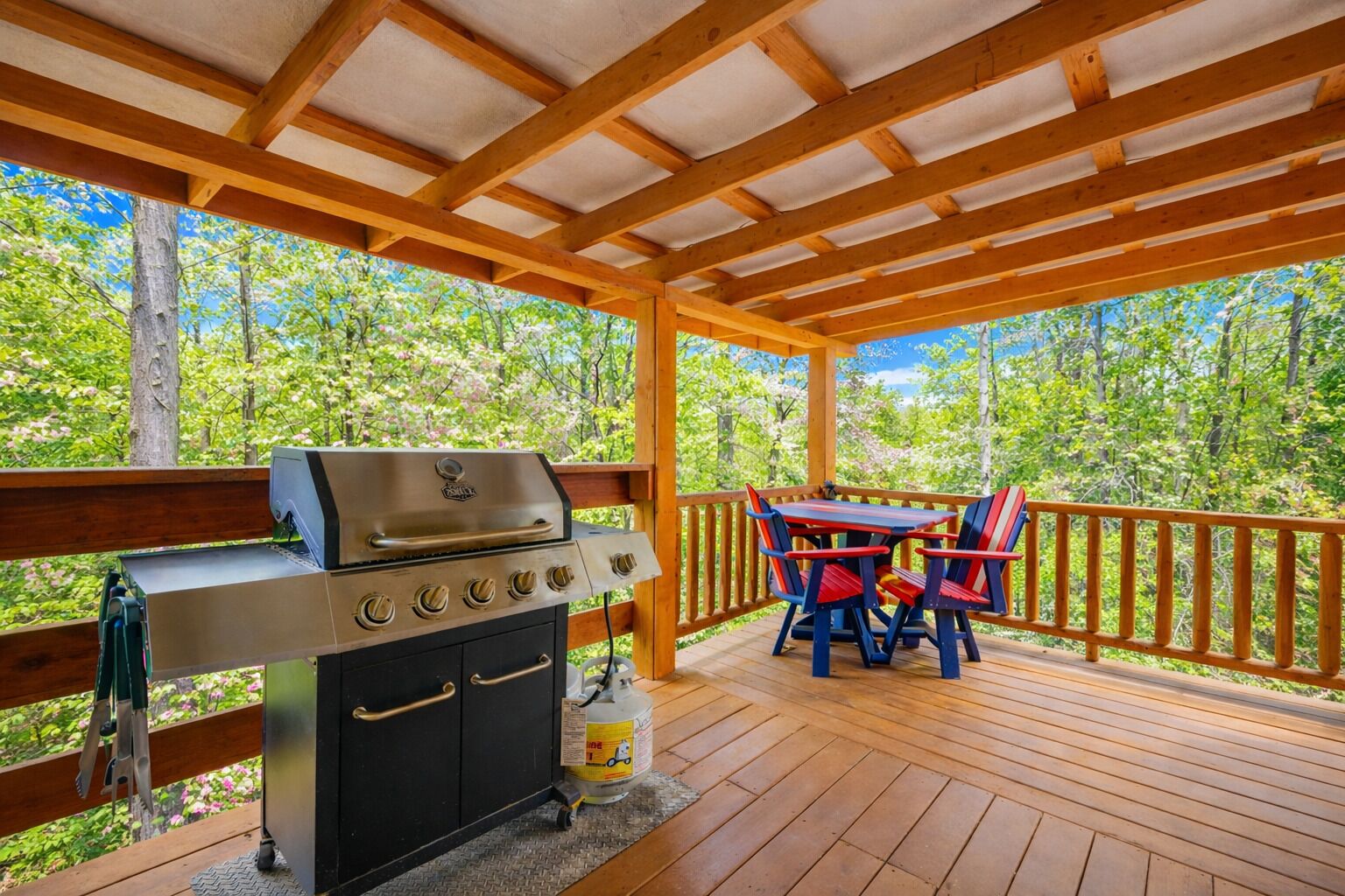 An outdoor deck with a grill and a table with chairs.