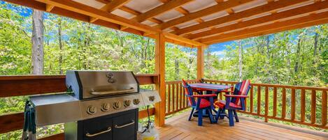 An outdoor deck with a grill and a table with chairs.