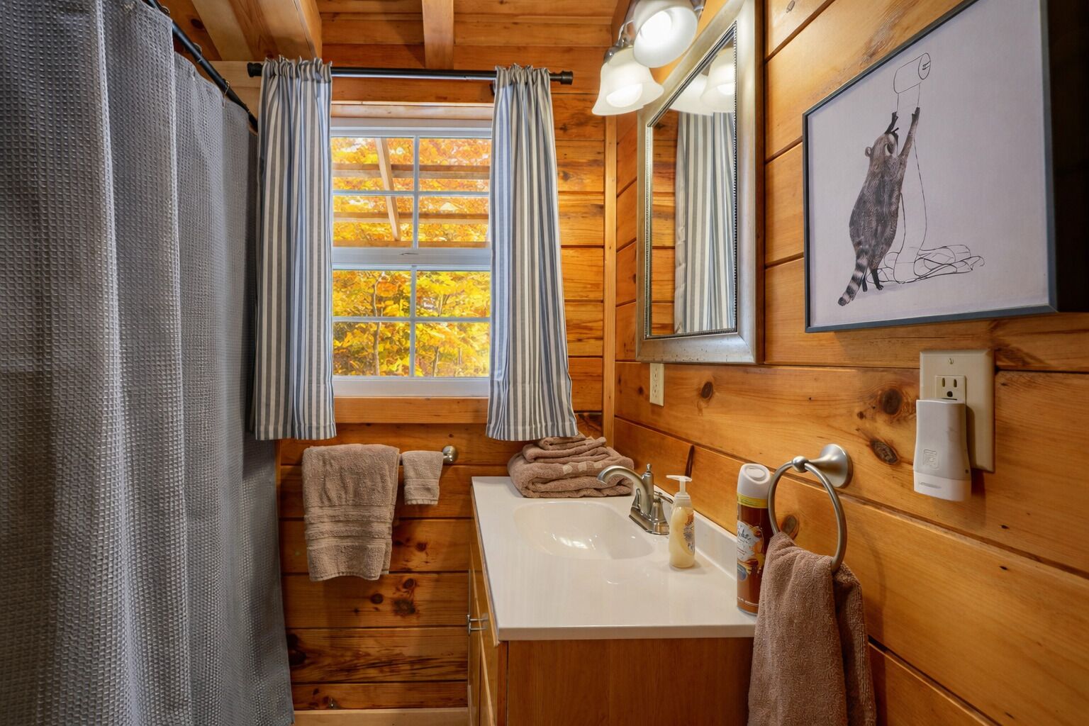 Ein Badezimmer einer Holzhütte mit Fenster, Waschbecken und Spiegel.