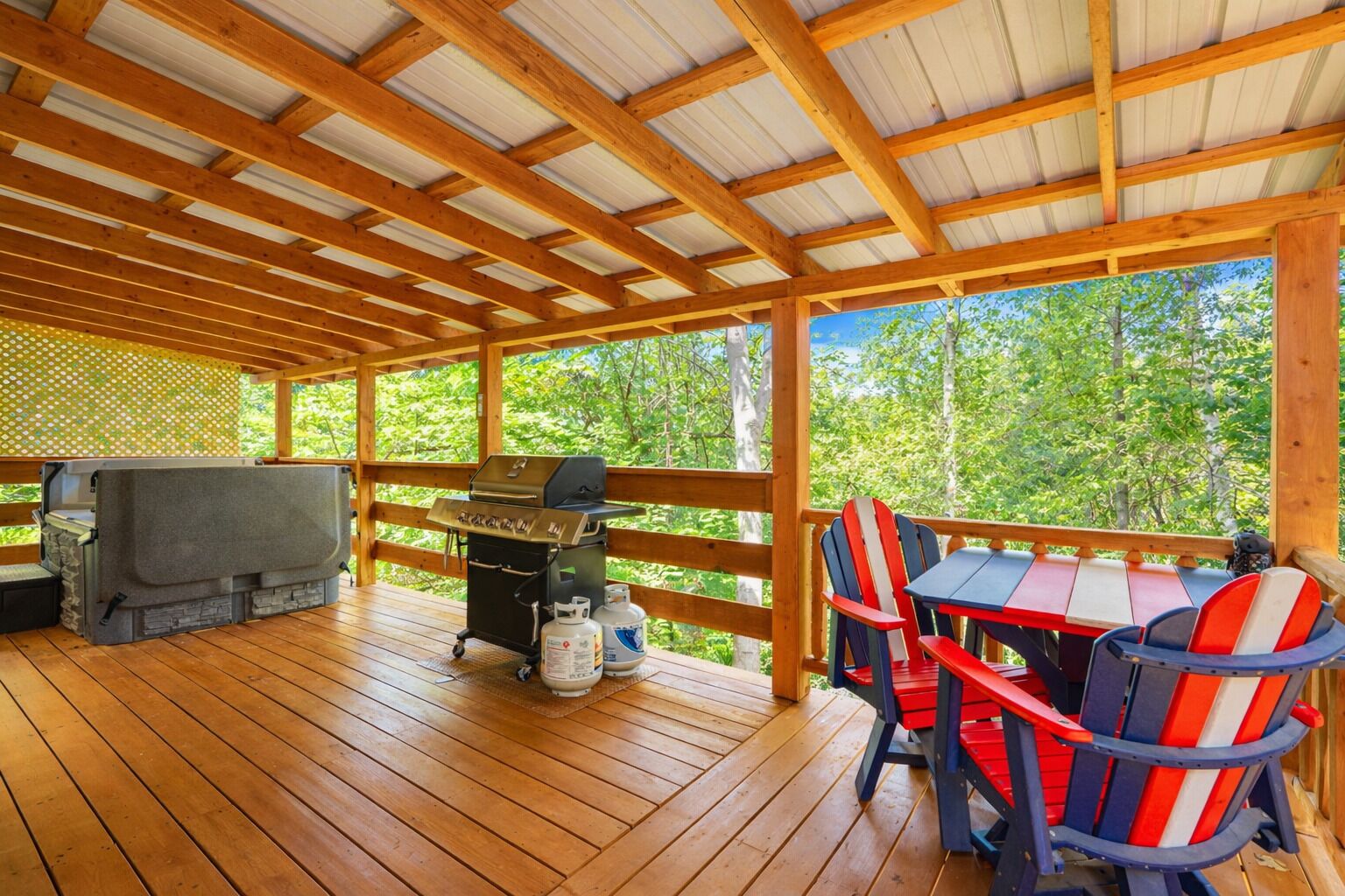 Une terrasse extérieure avec un barbecue, des sièges et une vue sur la forêt.