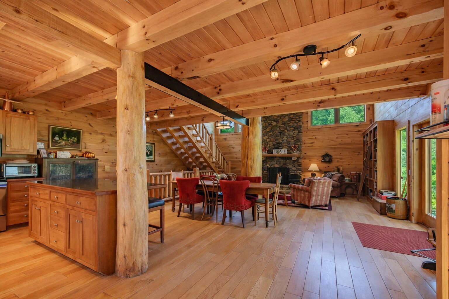 A wooden cabin interior with a kitchen, dining area, and living room.