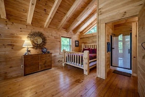 A wooden cabin interior with a bed, dresser, and a mirror on the wall. - Pumpkin Ridge Resort: 2 spaces for one rate (New Plymouth)