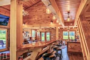A wooden interior with a bar area, seating, and large windows.
