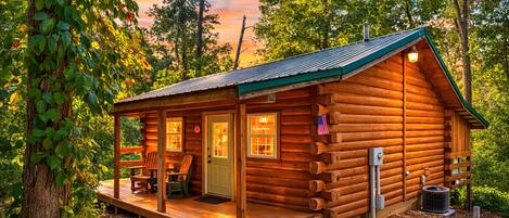 Eine Blockhütte mit Veranda, zwei Stühlen, einer Tür und einer amerikanischen Flagge.
