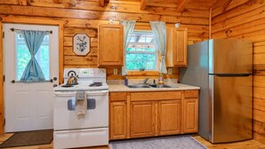 Una cocina compacta con armarios de madera, una estufa blanca, un fregadero y un refrigerador.