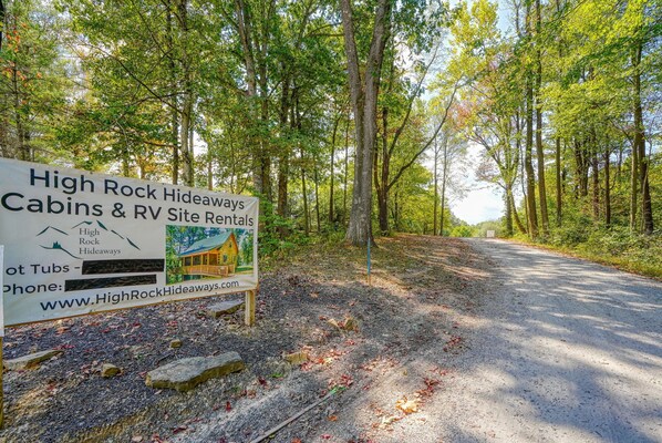A sign for High Rock Hideaways Cabins & RV Site Rentals with a forested backdrop.