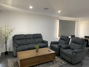 A modern living room with a grey sofa set, a wooden coffee table, and a potted plant.