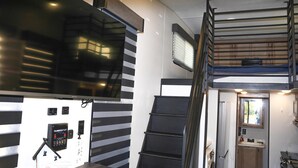Une pièce compacte et moderne avec un mur à rayures noires et blanches, un bureau intégré avec un ordinateur et une petite fenêtre.
