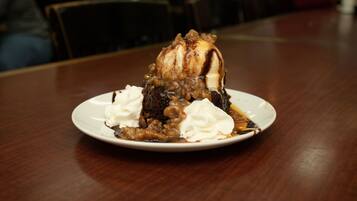 Dessert auf einem weißen Teller mit Karamellsauce und Schlagsahne auf einer Holztischplatte.