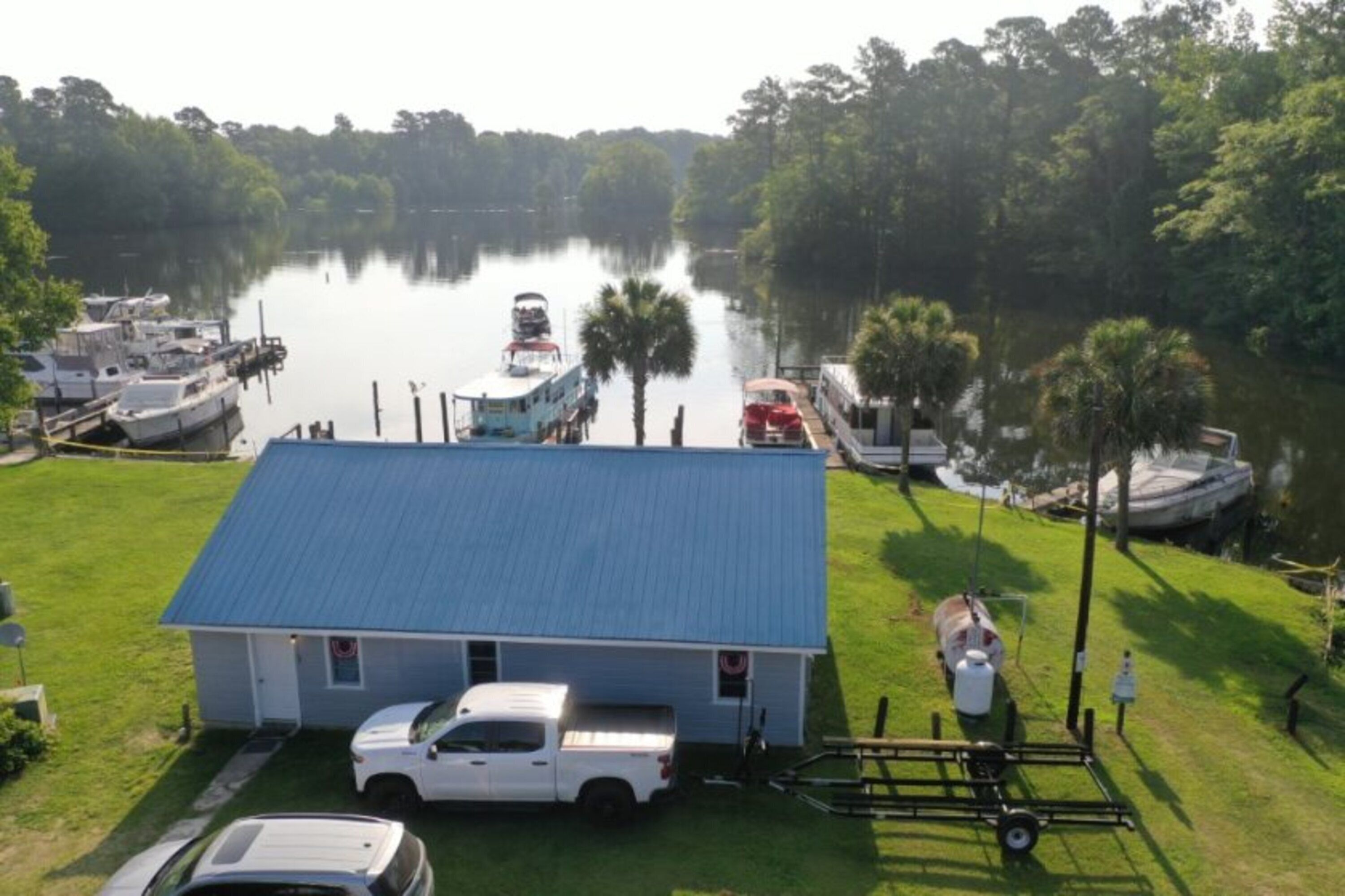 A lakeside property with a dock, boats, and a house with a blue roof.