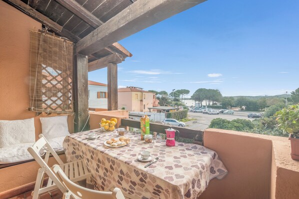A balcony with a table set for breakfast, including pastries, a coffee maker, and a cup. - Piazzetta Bilo Brezza Marina (Loiri Porto San Paolo)