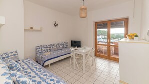 A compact living space with a sofa, a dining table, and a TV. - Piazzetta Bilo Brezza Marina (Loiri Porto San Paolo)