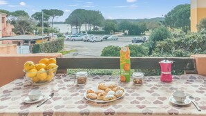 A balcony with a table set for breakfast, including a bowl of lemons, a plate of pastries, and a coffee maker. - Piazzetta Bilo Brezza Marina (Loiri Porto San Paolo)