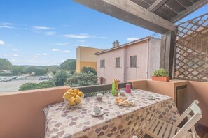 A balcony with a table set for tea, a bowl of lemons, and a plate of pastries. - Piazzetta Bilo Brezza Marina (Loiri Porto San Paolo)