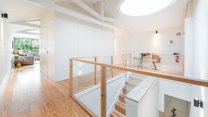 A modern interior with a wooden staircase, a glass railing, and a view of the outdoors.