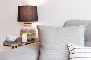 A cozy living room with a grey sofa, a small side table with a lamp, a decorative vase, and a white candle. - Modern loft in the heart of Porto (Porto)
