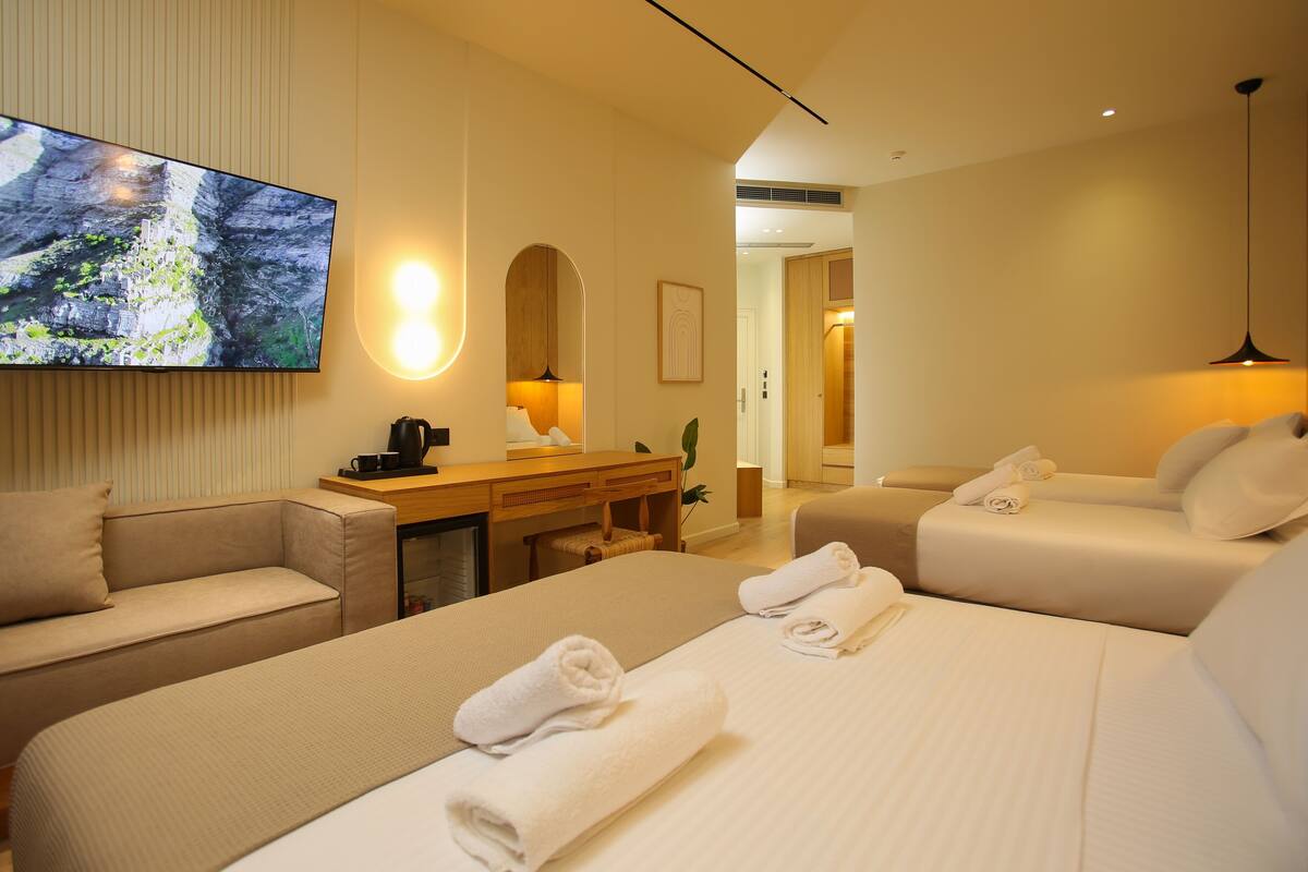 A hotel room with two beds, a desk, a TV, and a mirror.