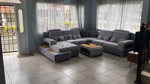 Een moderne woonkamer met een hoekbank, een salontafel en een trap.