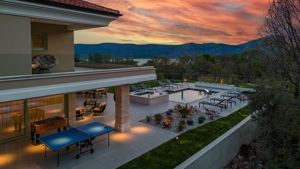 Ein modernes Haus mit Pool, Sitzgelegenheit im Freien und Blick auf die Berge bei Sonnenuntergang.