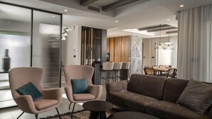 Ein modernes Wohnzimmer mit einer Couch, zwei Sesseln, einem Couchtisch und einem Essbereich mit Tisch und Stühlen.