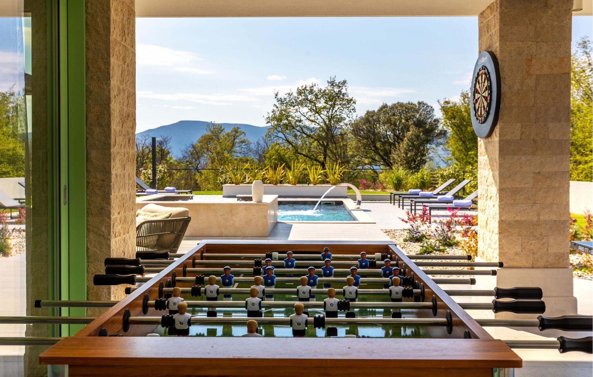 Uma mesa de pebolim em área com piscina, com vista para uma montanha e para a piscina.