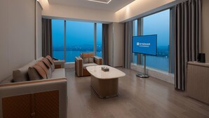 A modern hotel room with a large window, a flat-screen TV, a sofa, a coffee table, and a cabinet. - Wyndham Shaoxing Keqiao (Shaoxing)