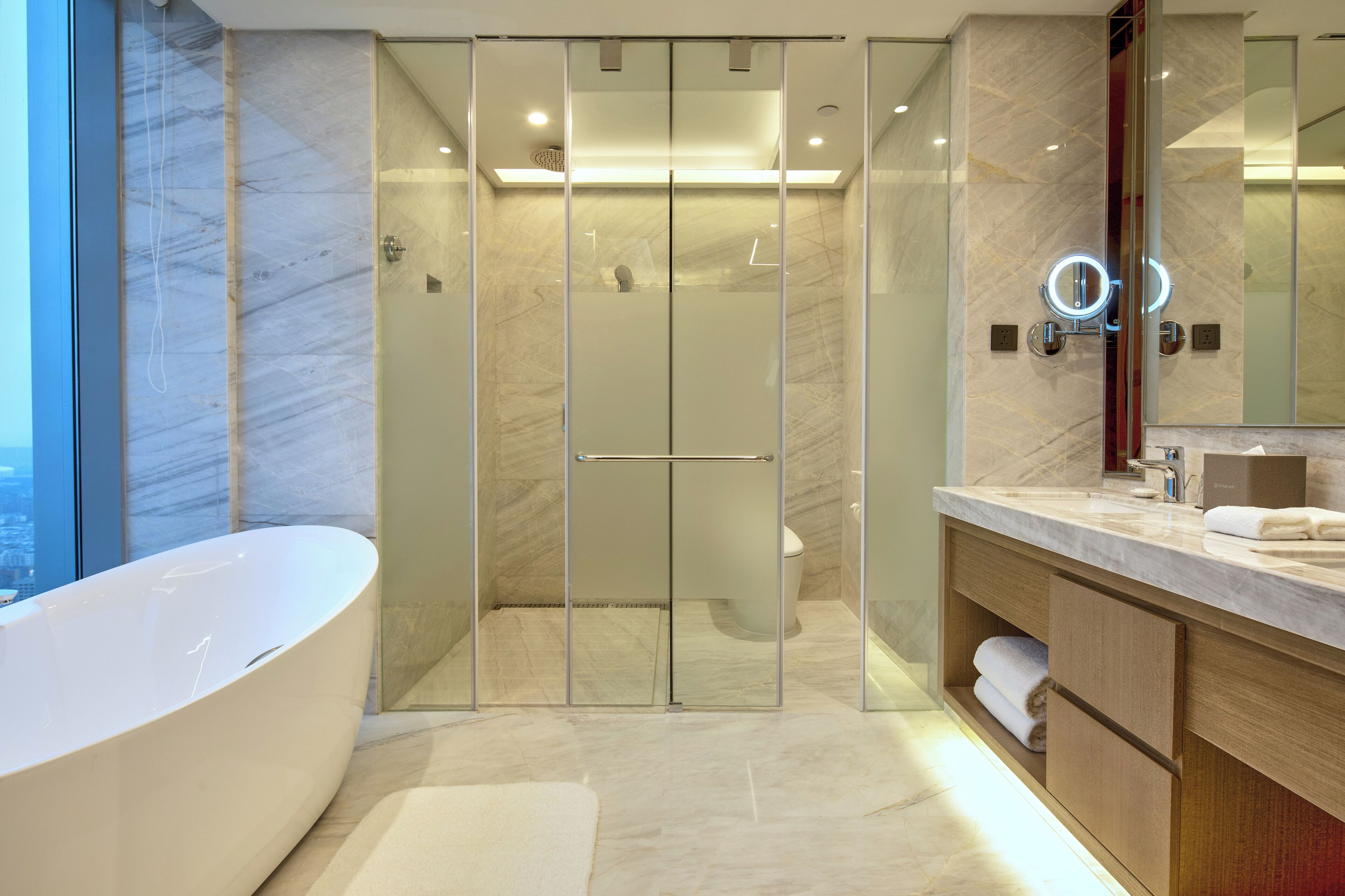 Un baño moderno con ducha envuelta en vidrio, una bañera independiente y un tocador con espejo.