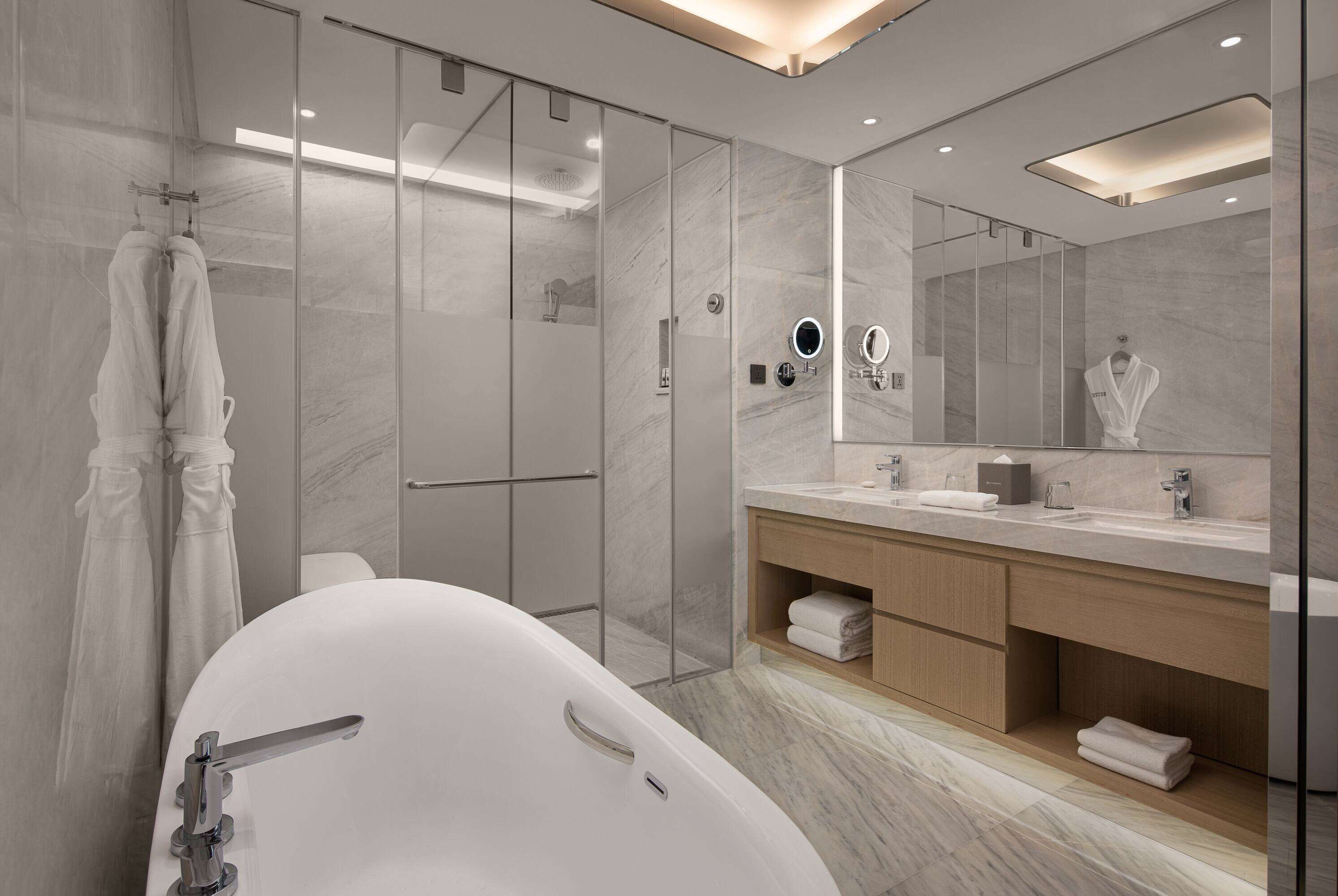 A modern bathroom with a freestanding bathtub, a glass-enclosed shower, and a large mirror above the vanity.