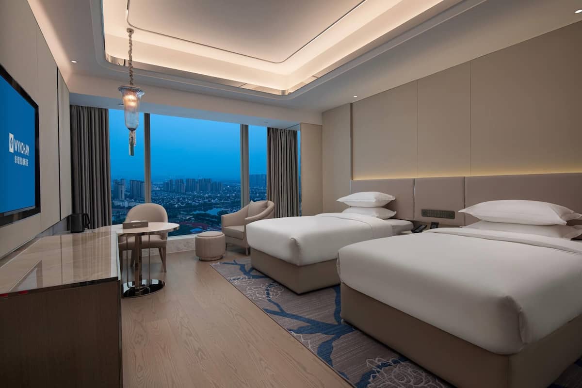 Ein Hotelzimmer mit Blick auf die Stadt, mit zwei Betten, einem Schreibtisch und einem Stuhl.