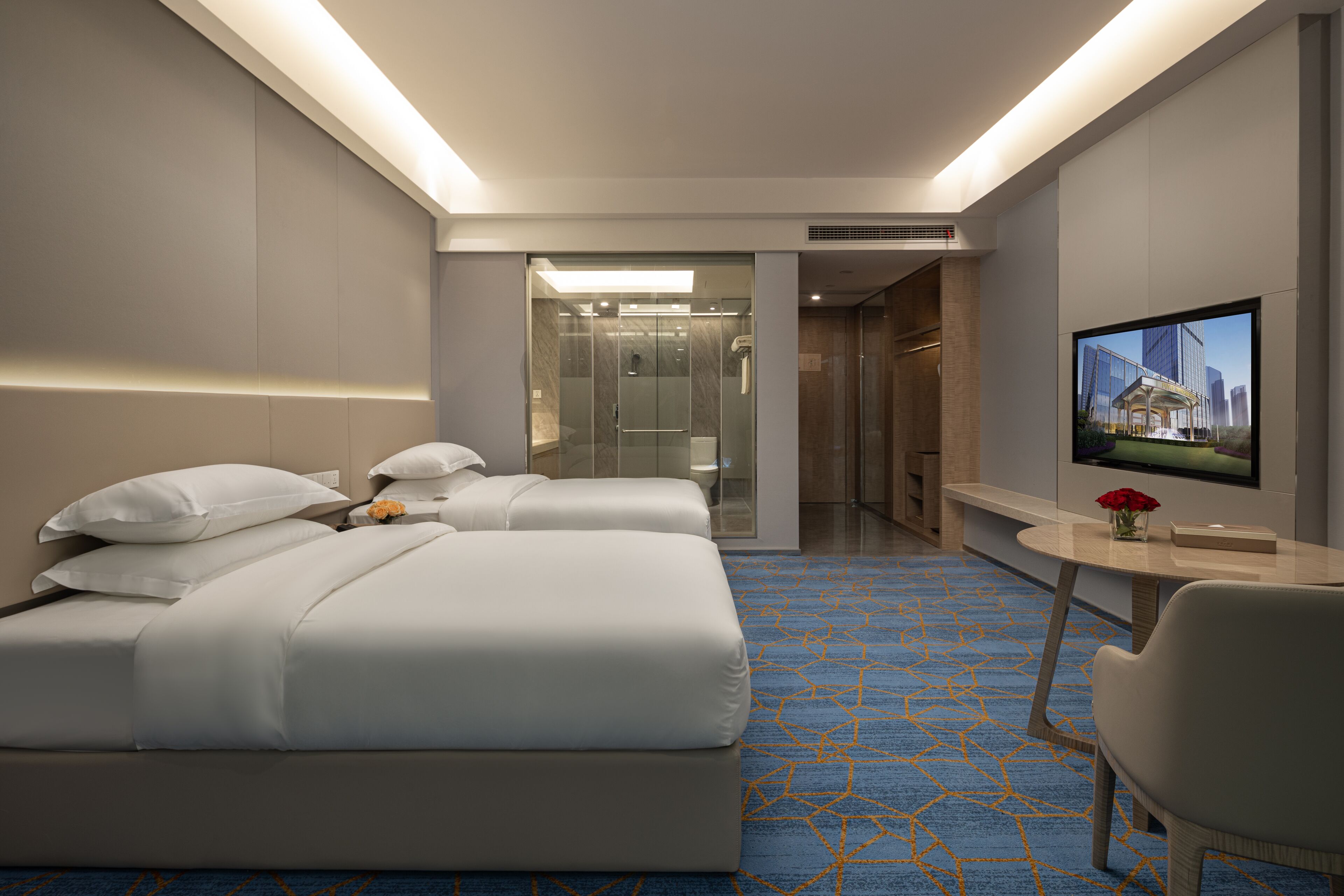 A modern hotel room with a large bed, a desk, a TV, and a shower area.
