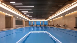 A long indoor swimming pool with a tiled floor, surrounded by walls with large windows. - Wyndham Shaoxing Keqiao (Shaoxing)