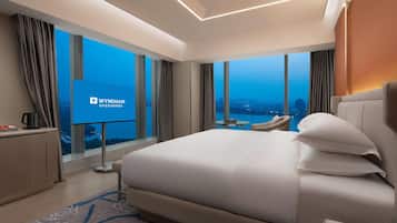 Una habitación de hotel moderna con una cama grande, un escritorio y una pantalla de televisión mostrando el logotipo de Wyndham.