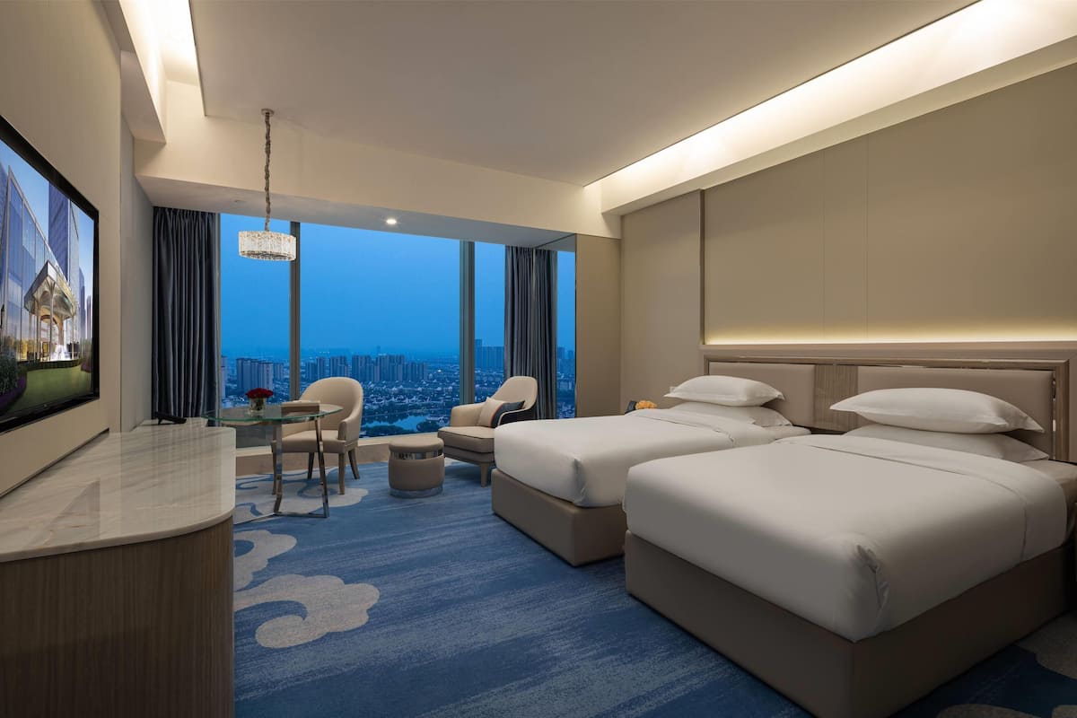 Ein Hotelzimmer mit einem großen Bett, einem Schreibtisch, einem Sessel und einem Fernseher.
