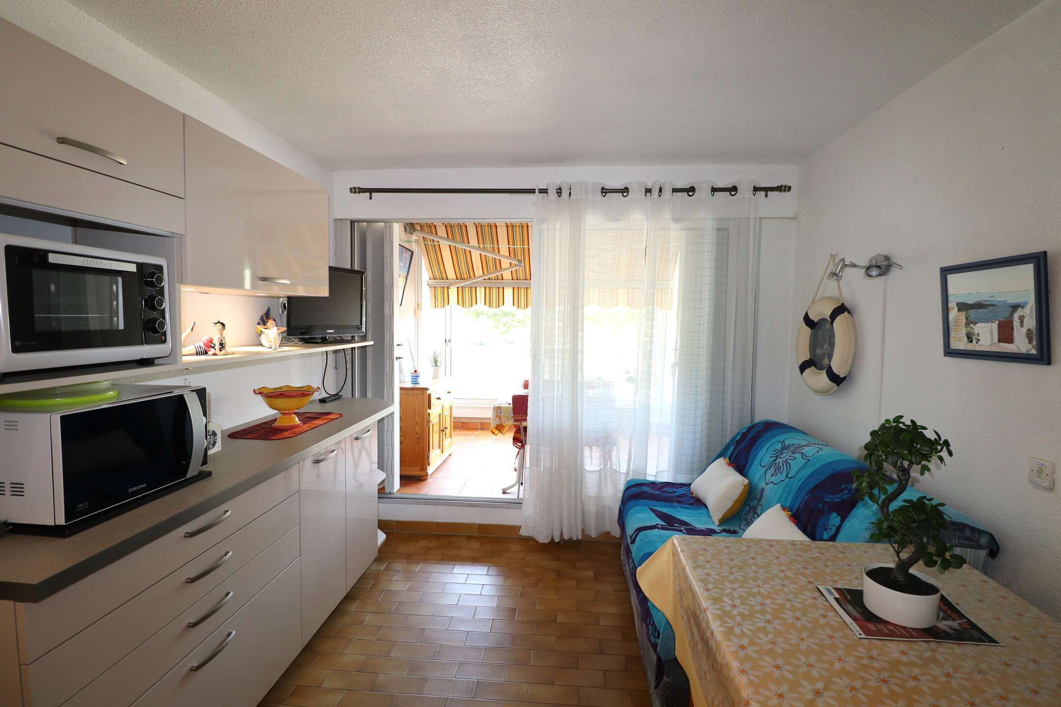 A compact living space with a kitchenette, a dining area, and a view into the dining room.