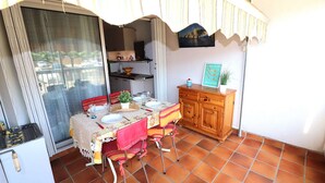 Un pequeño comedor con una mesa dispuesta para dos, un refrigerador y un armario de madera.