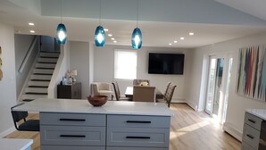 A modern kitchen with a central island, wooden flooring, and pendant lighting. - Tranquil Lakefront home. Premium accommodations, newly remodeled (Hamlin)