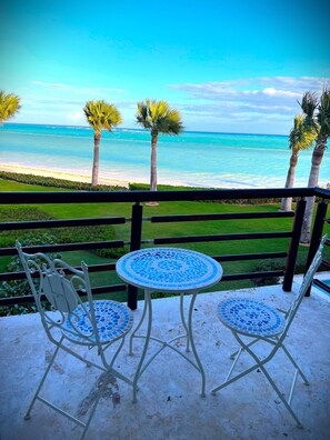 A balcony with a view of the ocean, featuring two white metal chairs and a small round table with blue mosaic tiles. - (20% OFF) Artsy & Chic Oceanfront hideaway: exclusive Cap Cana Marina district (CAP CANA)