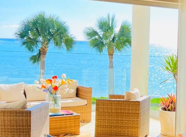 A balcony with wicker furniture, a vase with flowers, and a view of the sea. - (20% OFF) Artsy & Chic Oceanfront hideaway: exclusive Cap Cana Marina district (CAP CANA)