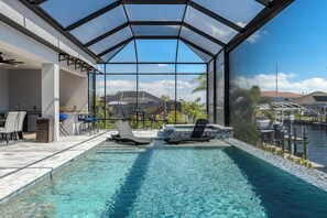 A swimming pool with lounge chairs, a covered patio area, and a view of the marina.