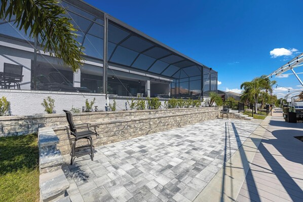 A modern outdoor patio area with a covered seating area, stone steps, and a view of the surrounding landscape.