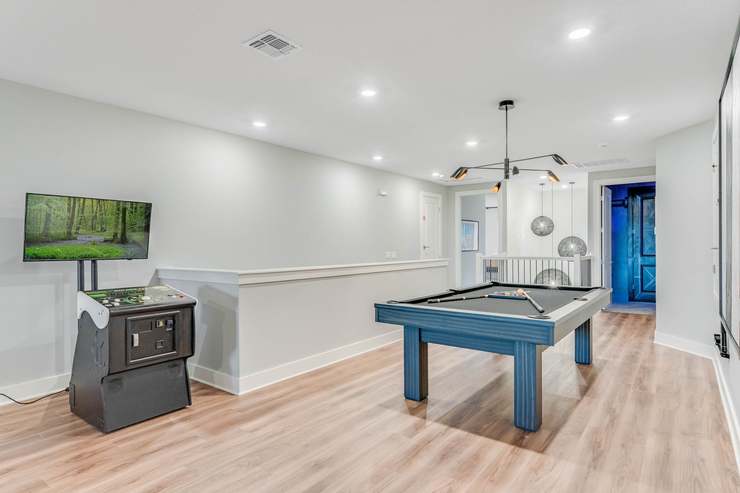 A modern room with a pool table, a gaming console, and a television on the wall.