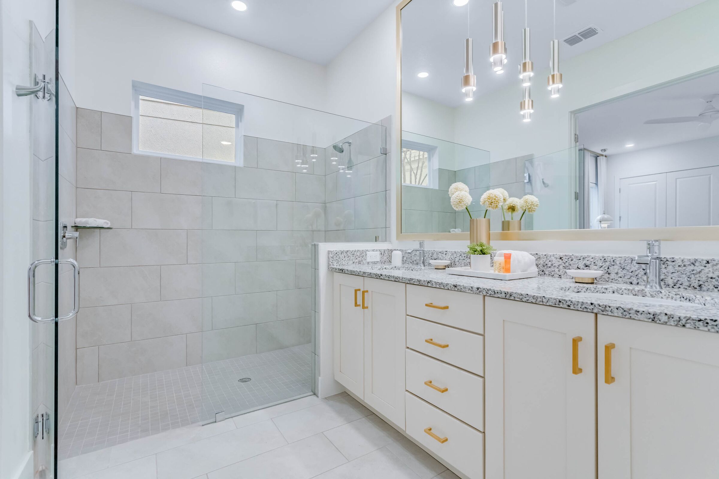 Un baño moderno con cabina de ducha, un espejo grande y encimera de granito.