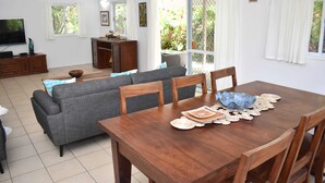 A dining area with a wooden table, chairs, and a grey sofa. - Tiare Taporo (Matavera District)