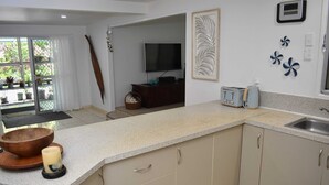 A kitchen with a granite countertop, wooden bowl, candle, and a TV on the wall. - Tiare Taporo (Matavera District)