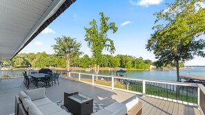 A deck with outdoor furniture, a view of a lake, and a gazebo.
