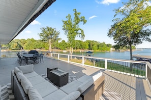 Una terraza con mobiliario exterior, vista a un lago y un pabellón.
