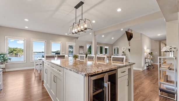 A spacious kitchen with a large island, white cabinetry, and a view of the outdoors.