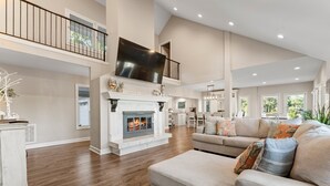 A spacious living area with a fireplace, a large sofa, and a high ceiling.
